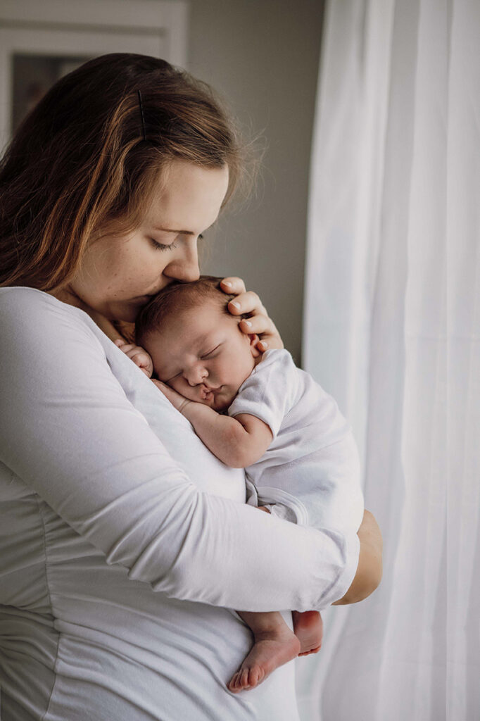 Mama hat den Jungen auf der Brust und Küsst ihn.
