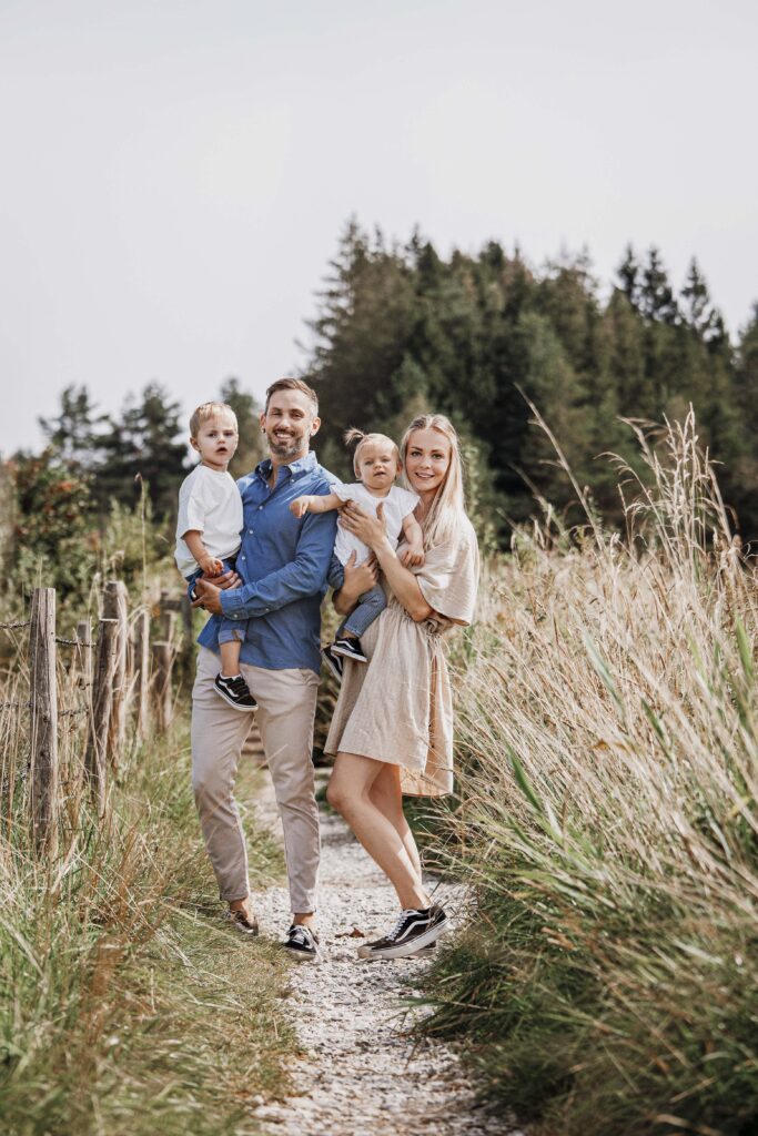 Familie steht am weg Rad, und jeder der Elternteile hat ein Kind auf dem arm.