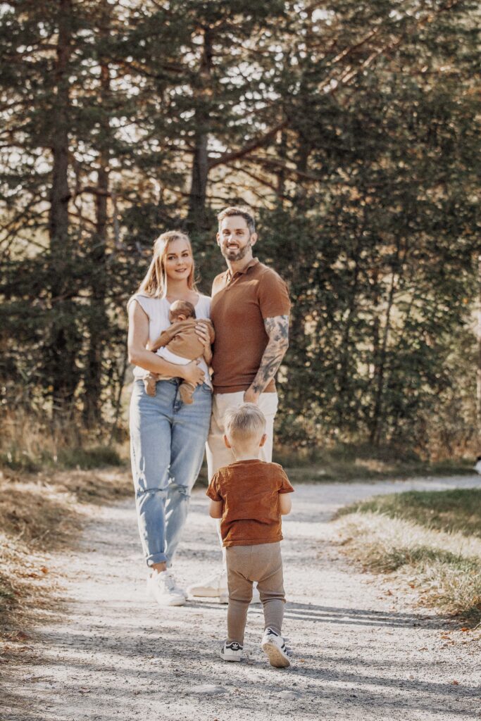 Familie steht in Füssen am Wald Rand und lässt den Jungen auf sich zu rennen.