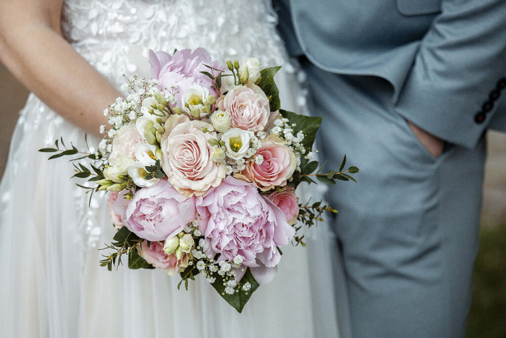 Blumenstrauß vor dem Kleid und dem Anzug.