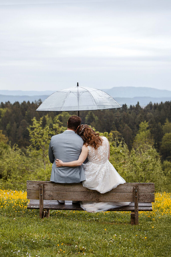 Brautpaar sitz unter dem Regenschirm und schaut auf den Zoller. Klosterkirchberg.