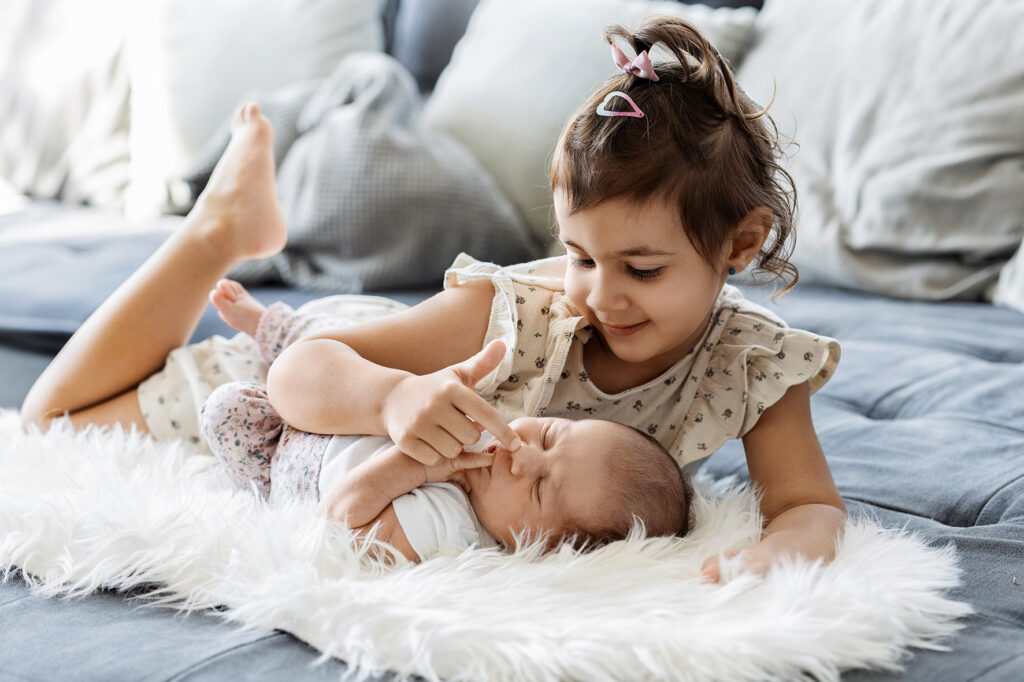 Große Schwester spielt mit dem Baby auf dem Fell. Sulz am Neckar.