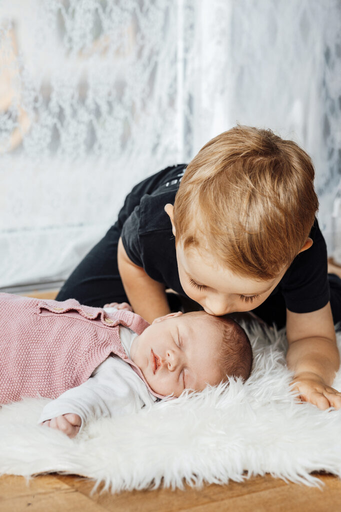 Großer Bruder Küsst das schlafende Baby auf dem Fell. Empfingen.