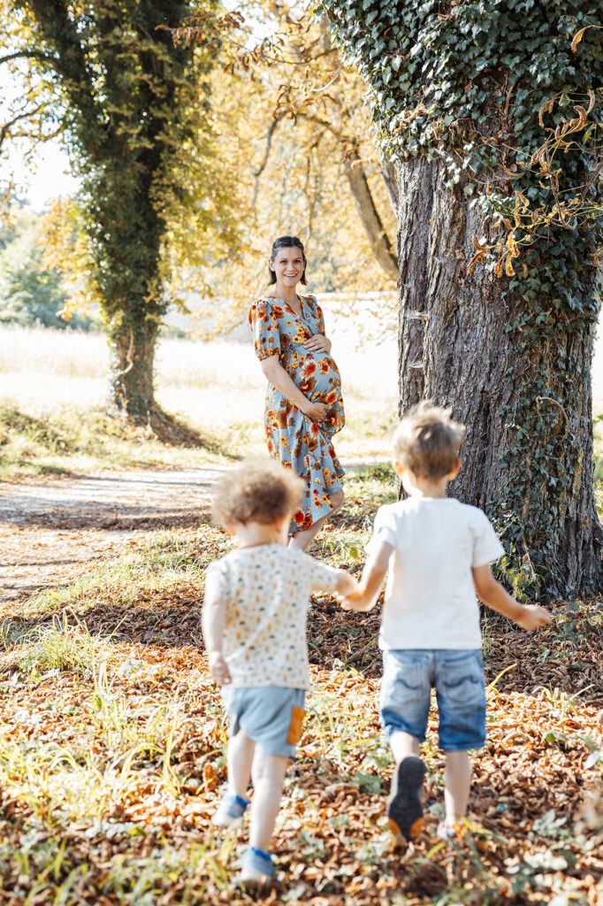 Schwangere, steht am Bauch im Fürstenpark in Inzigkofen. Kinder rennen auf sie zu.